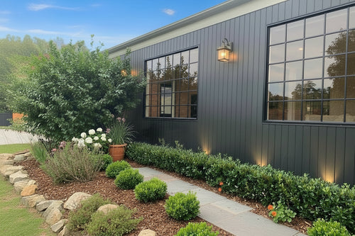 House exterior with black siding, windows, and a landscaped garden.